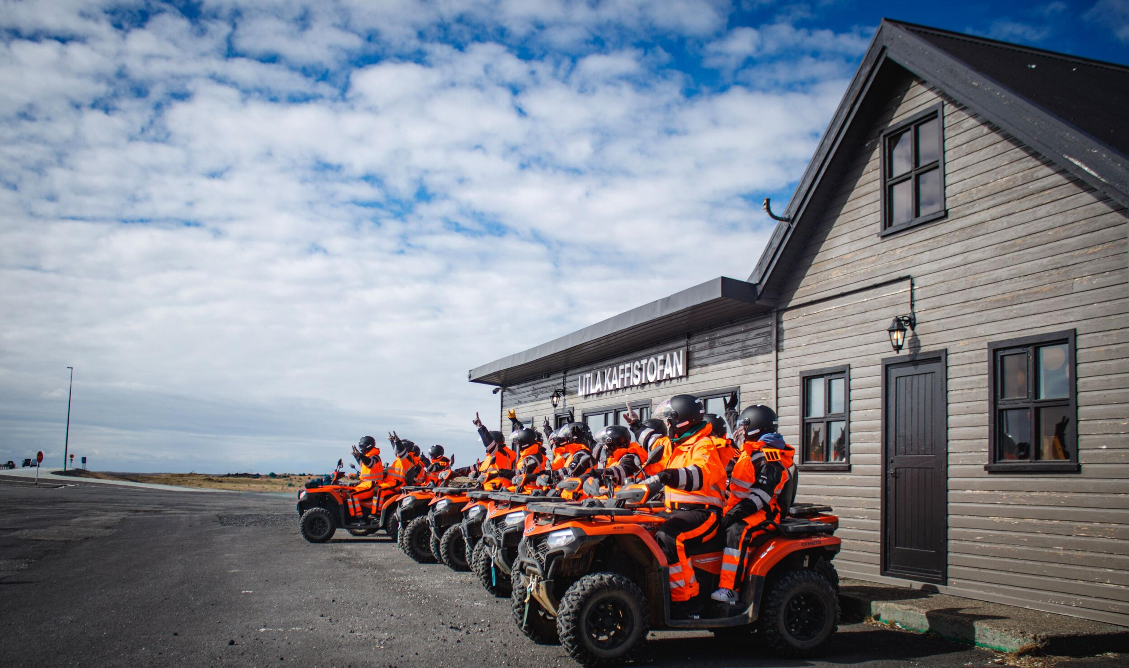 A row of people on ATVs in front of Litla Kaffistofan.