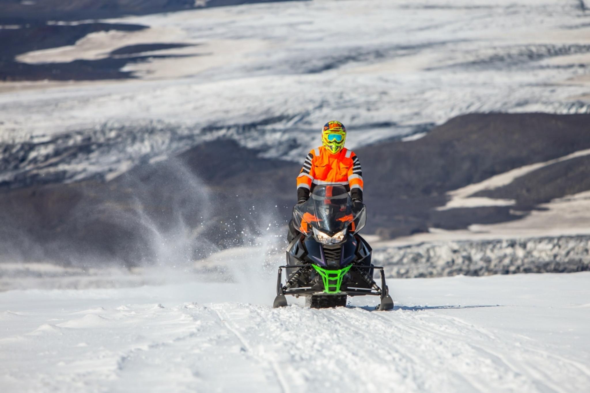 A single person snowmobiling on a vast snowy terrain.
