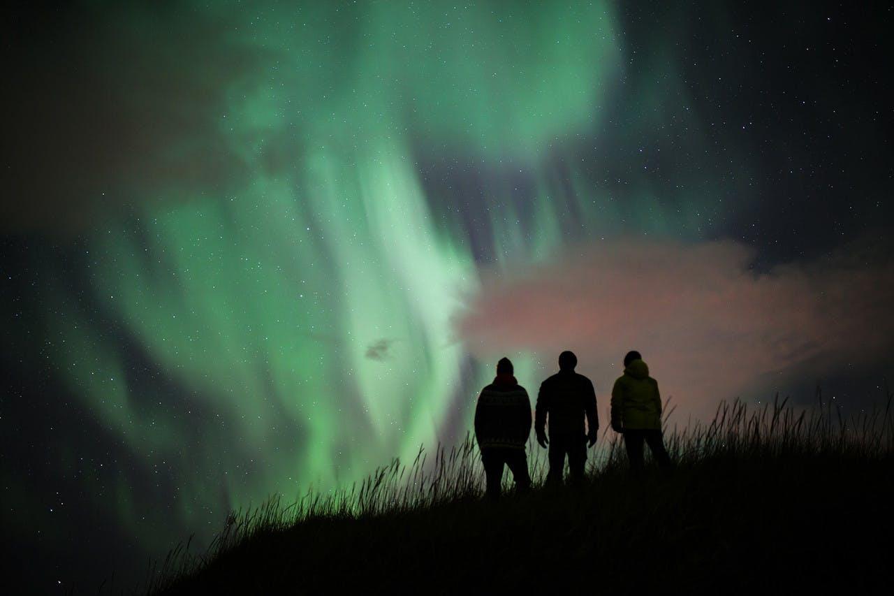 three people watching northern lights in Iceland