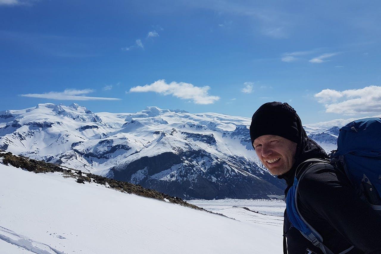 Iceland's highest peak Hvannadalshnúkur in the background with a smiling hiker looking at the camera