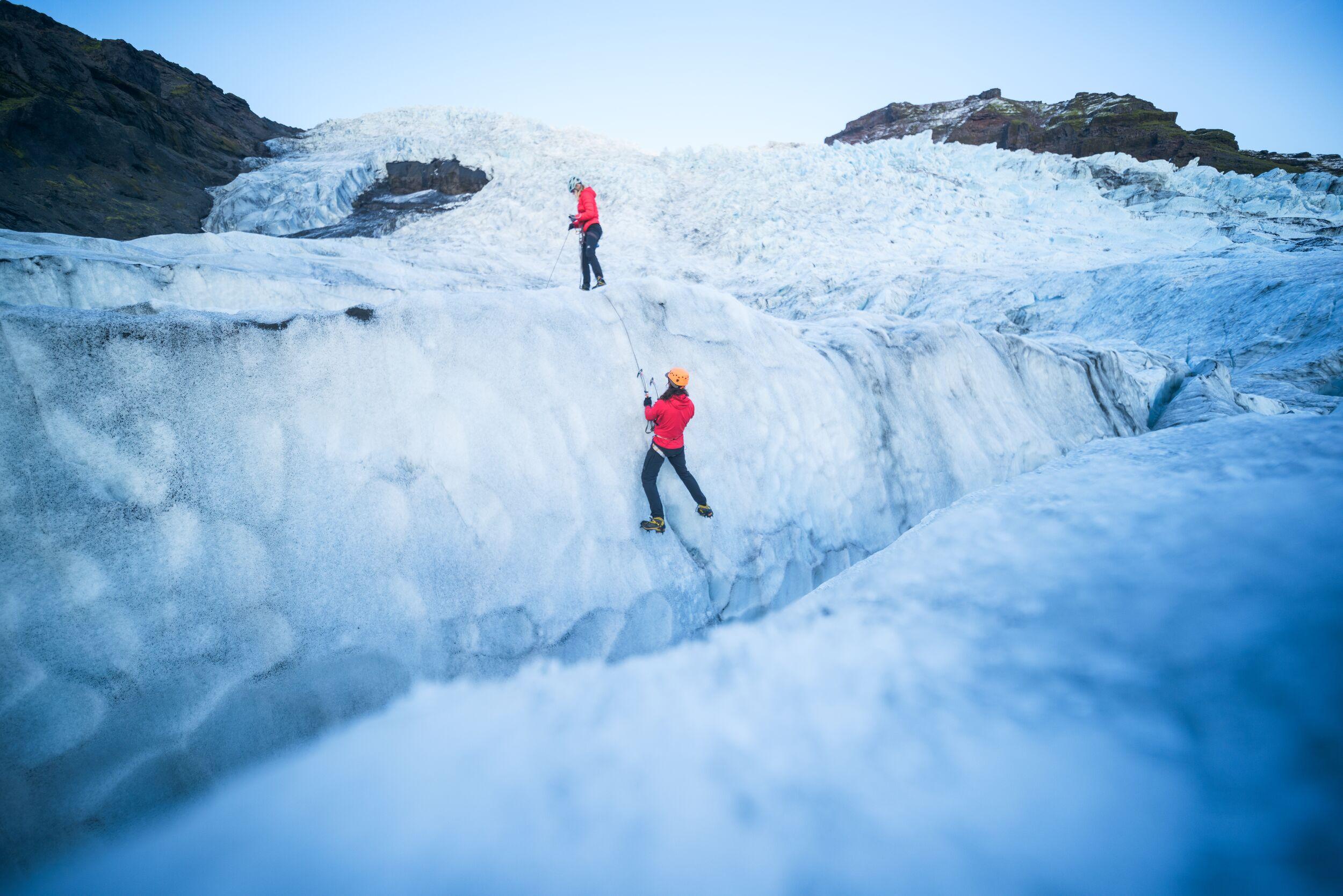 two people climbing ice on a glacier
