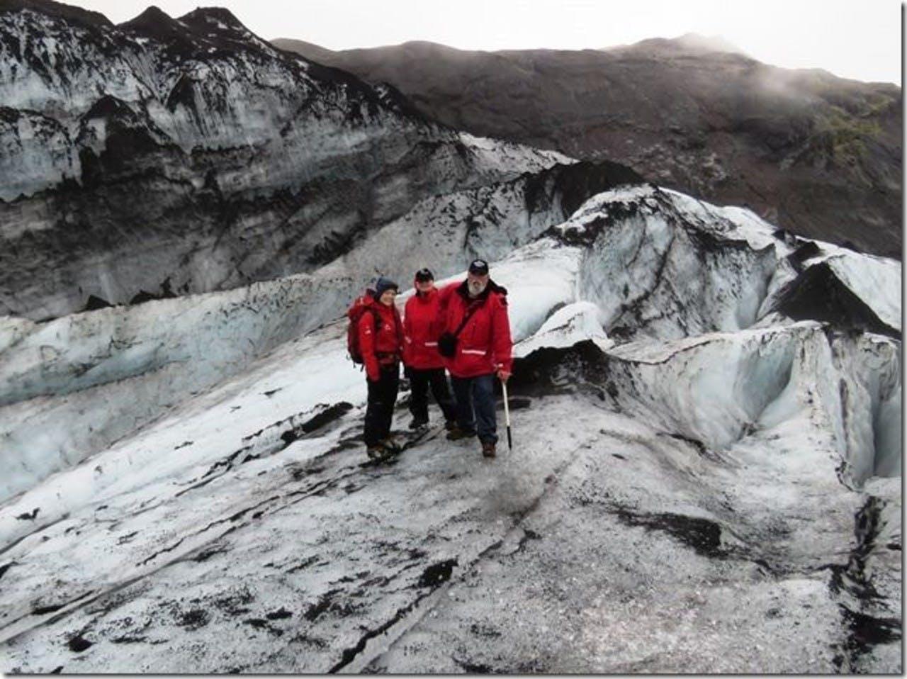 Three people wearing red standing on a glacier in Iceland