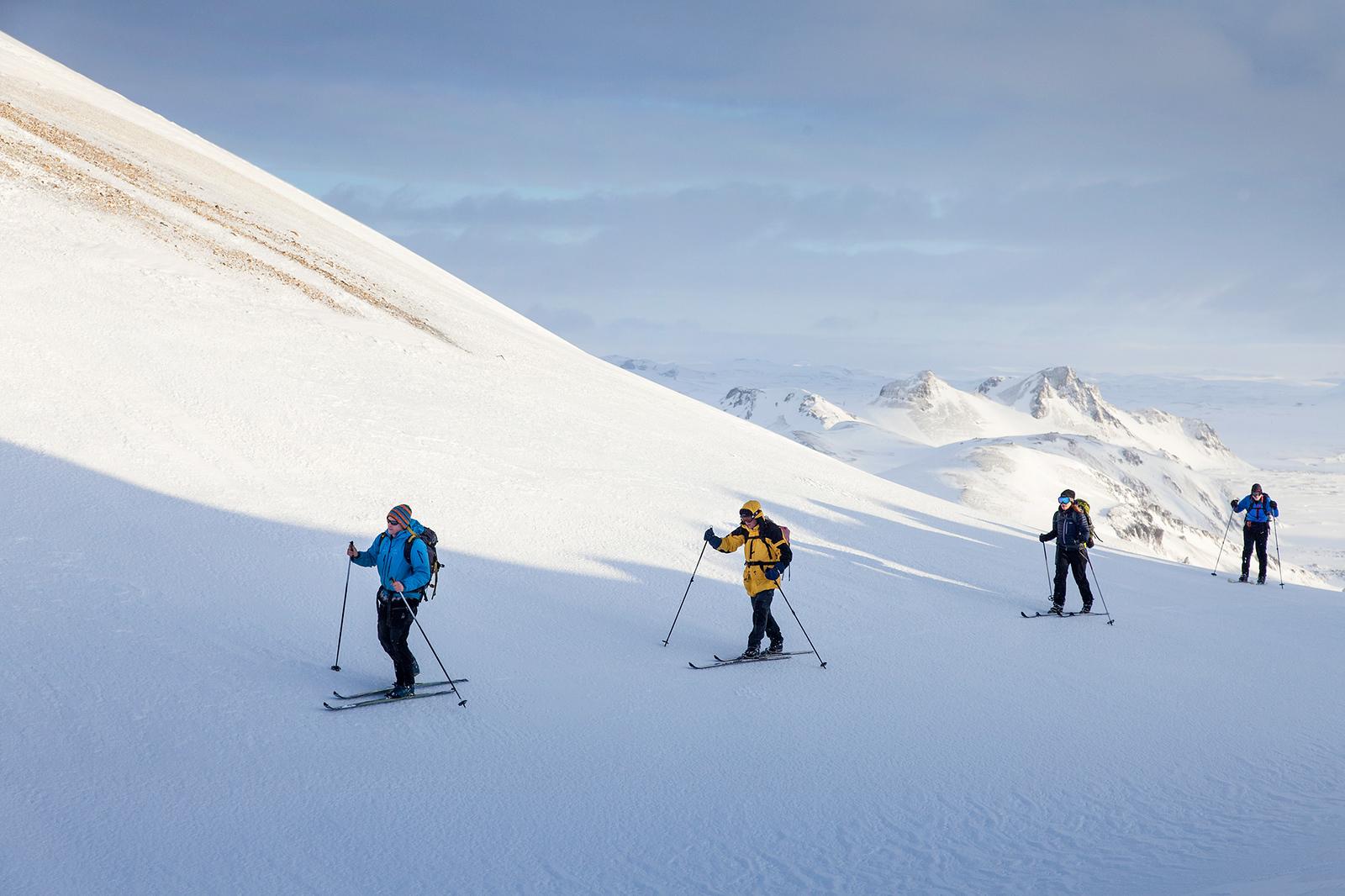 Hikers skiing in Landmannalaugar with beautiful mountains covered in snow in background