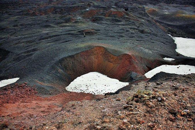 A picture of an area with black and red sand and a little snow