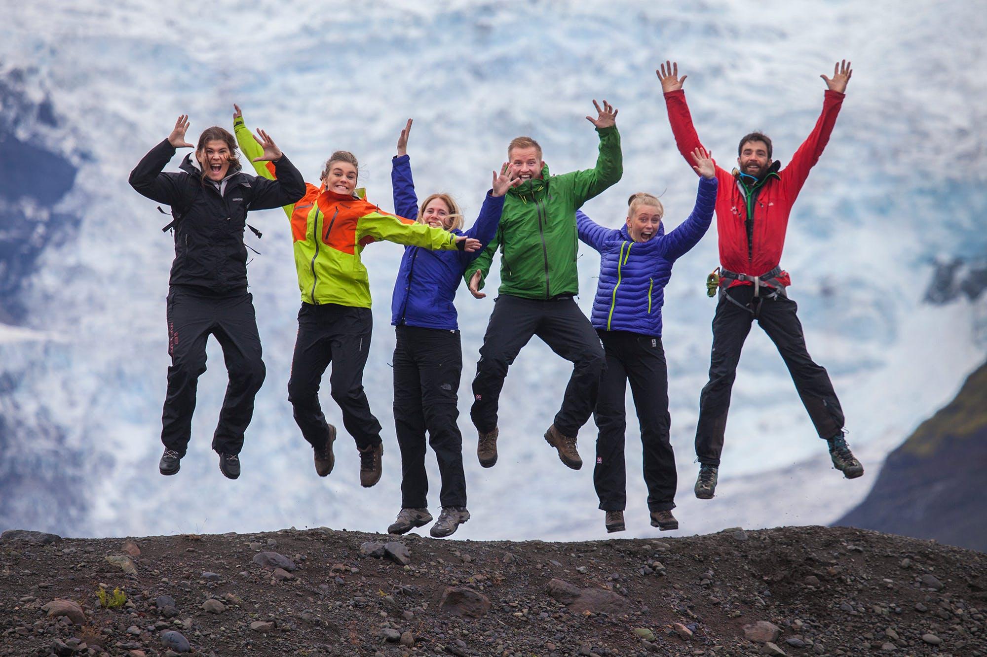 Group of people jumping in joy with a glacier in the background