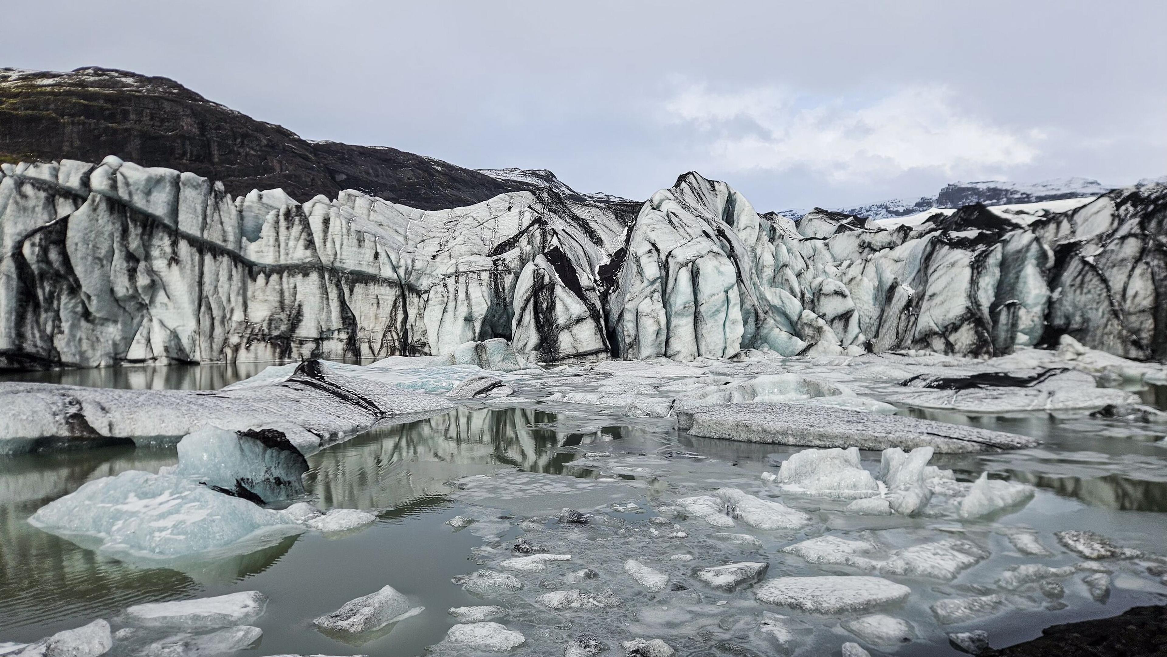 Ash-layered ice breaking off a glacier and into a glacier lagoon