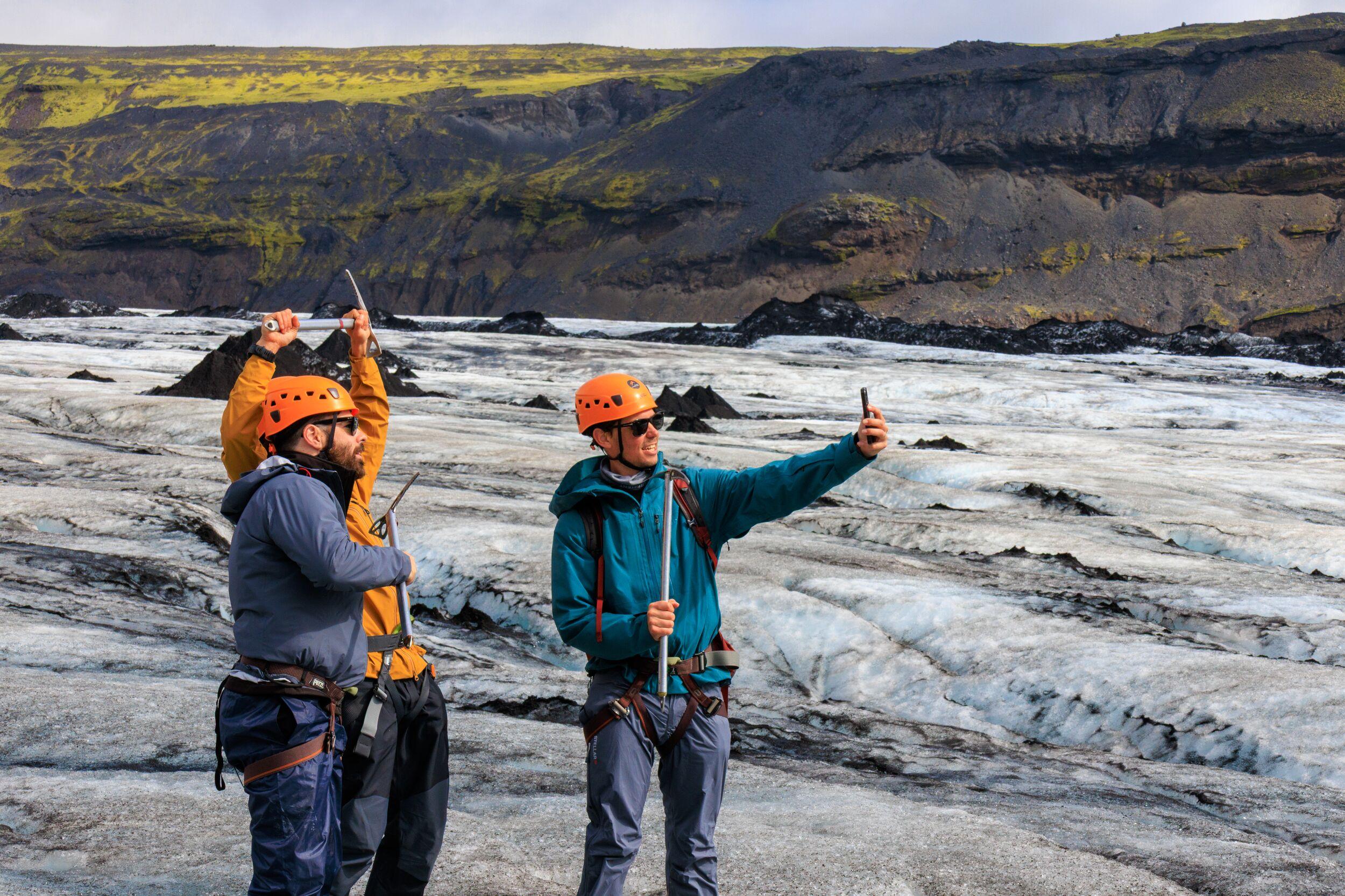 A group of hikers wearing helmets and carrying ice axes carefully explore the rugged terrain of Sólheimajökull glacier. A breathtaking Sólheimajökull glacier hike with views of deep crevasses and volcanic landscapes.