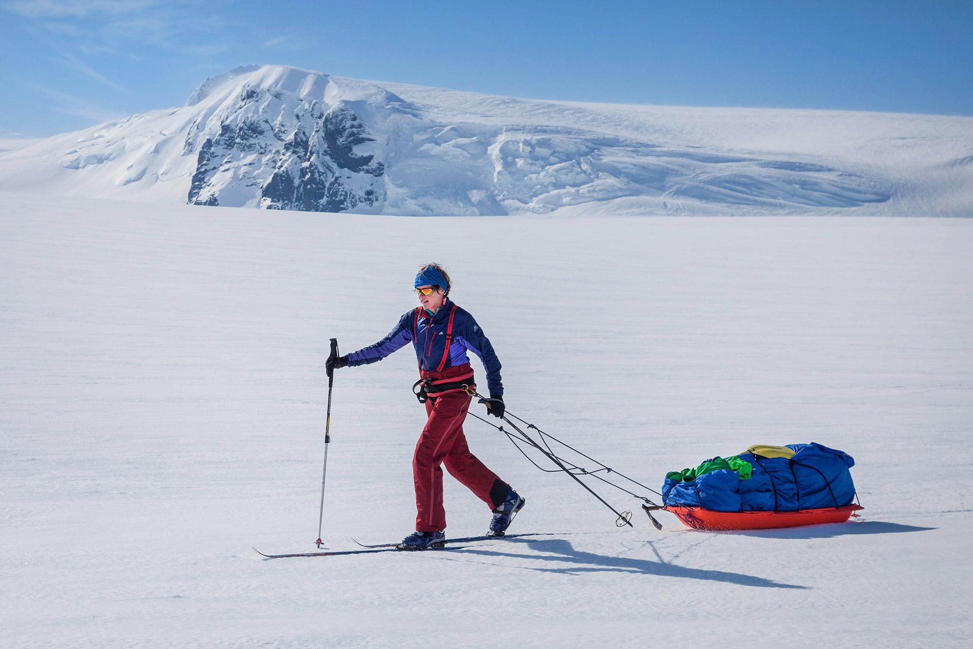A woman skiing on the glacier and a mountain standing out of the ice cap visible in the distance