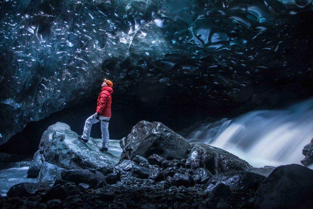 Inside dark ice cave with a waterfall inside