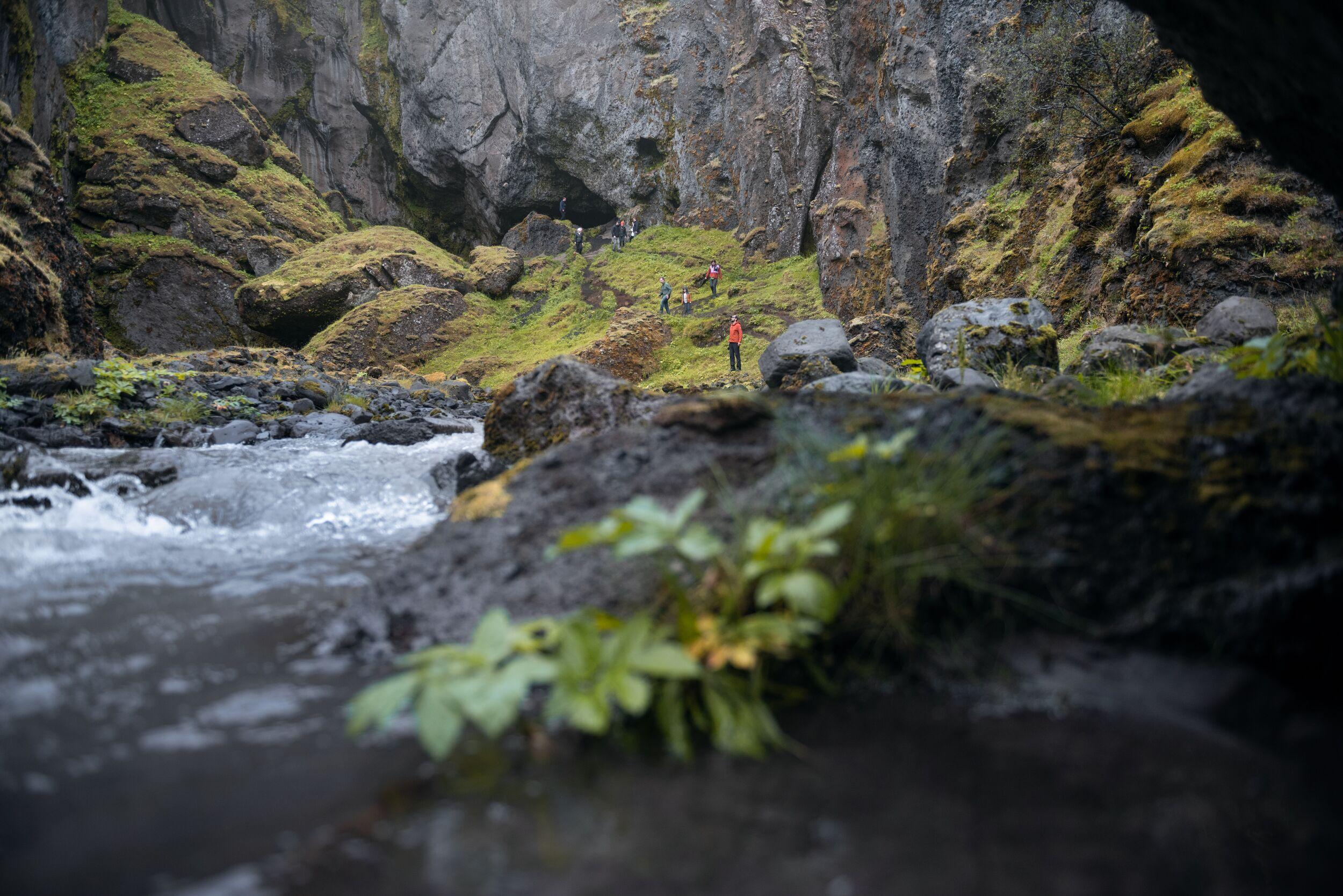 A group of hikers in a secret canyon next to a river in Þórsmörk valley
