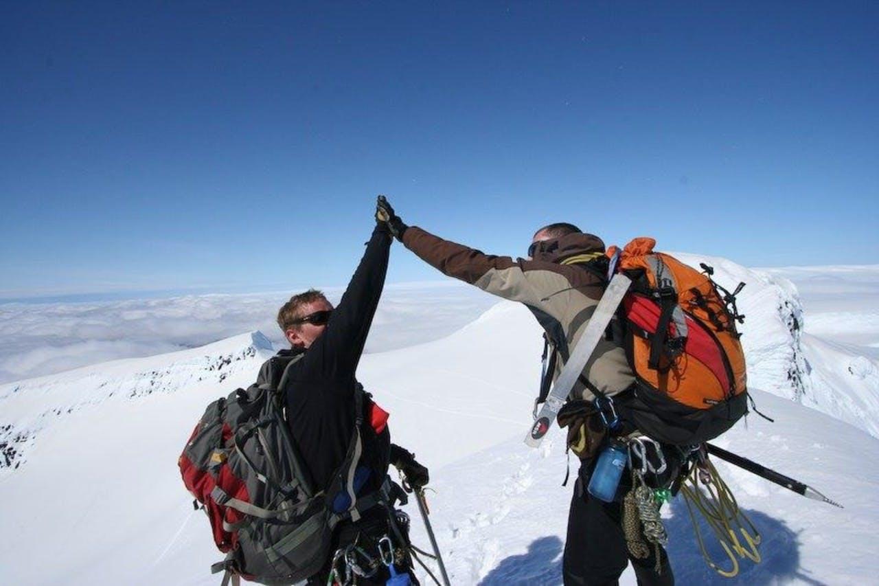 Two hikers giving each other a high five when they have reached the top of Hvannadalshnjúkur on a tour with Icelandic Mountain Guides.