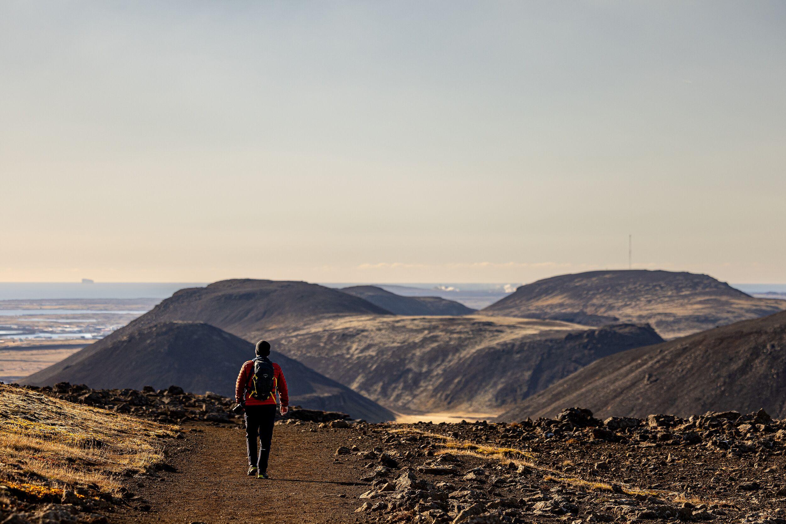 Volcanic hills with a hiker in Reykjanes lava field.