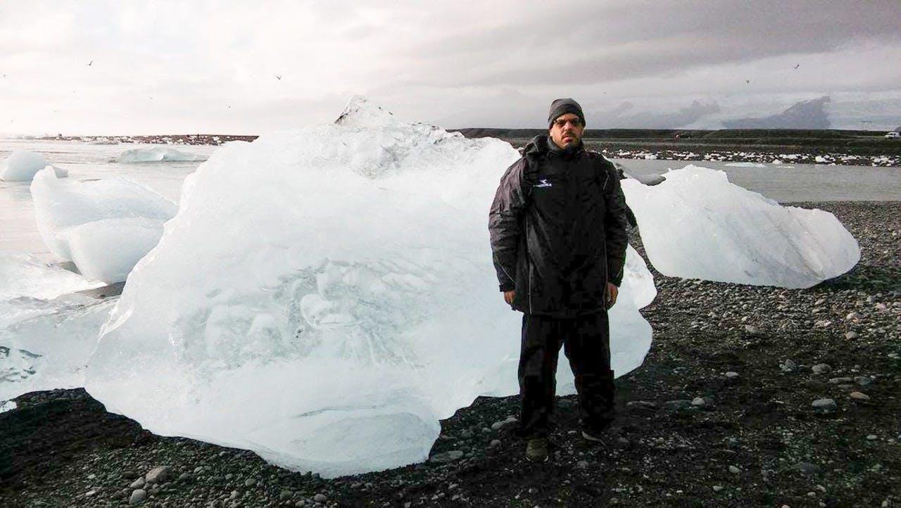 A man standing in front of a huge iceberg at Jökulsárlón in Iceland