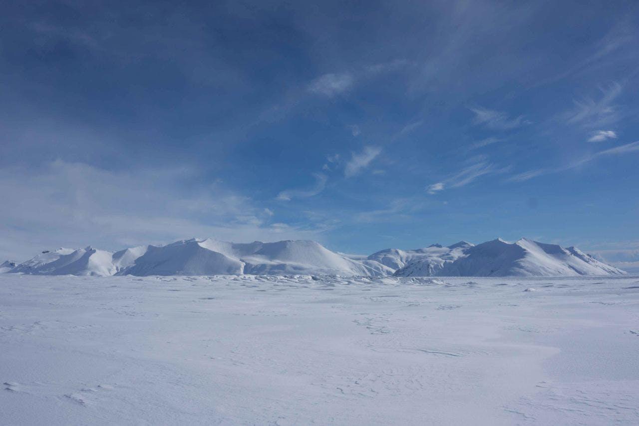View over snowy mountains with a blue sky.