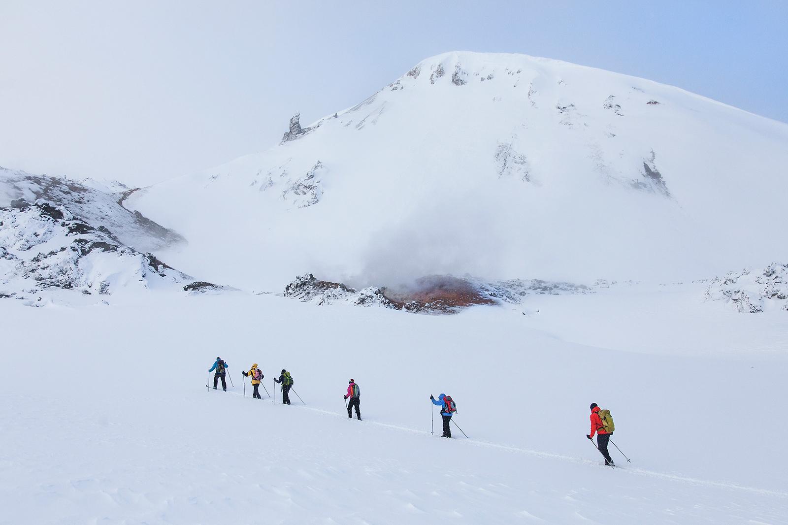 People hiking next to snowy mountain