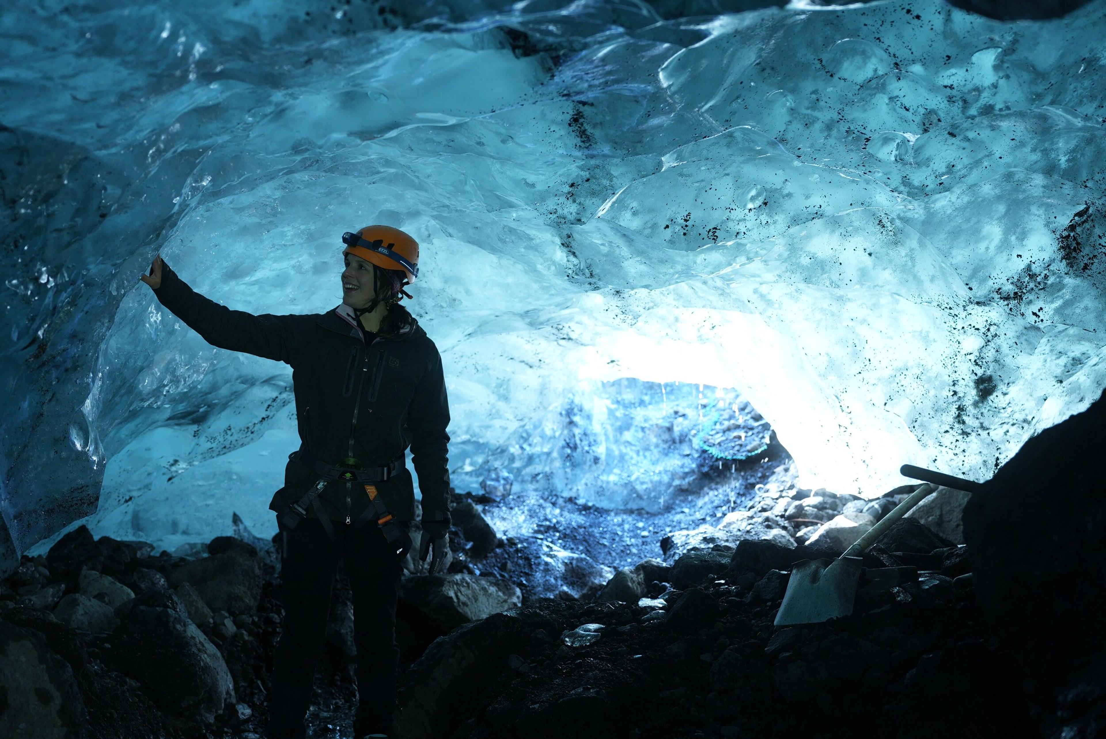 A smiling person admiring the blue ice inside an ice cave