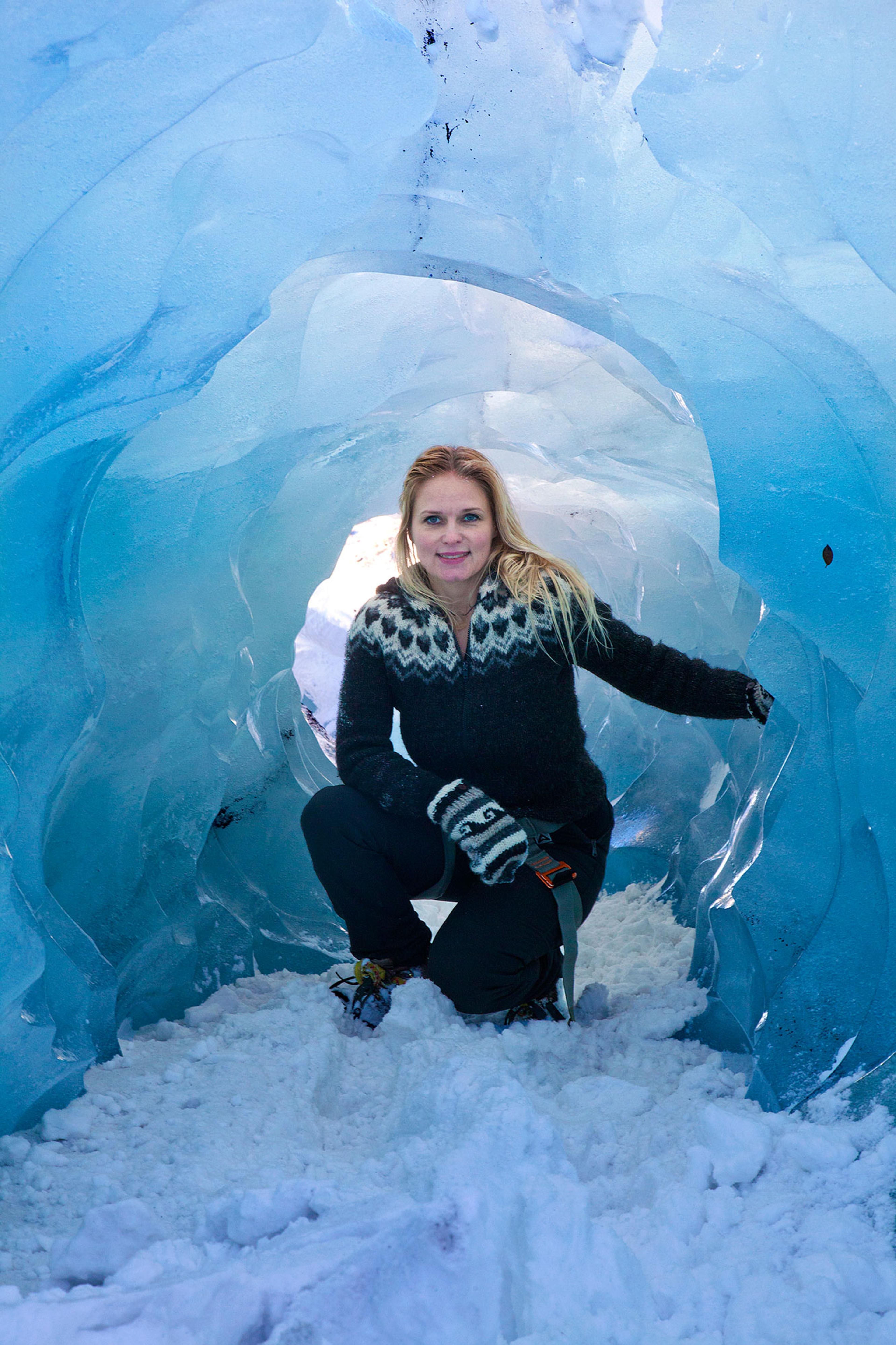 A woman in a ulla peysa (wool sweater) inside Solheimajokull (Sólheimajökull)
