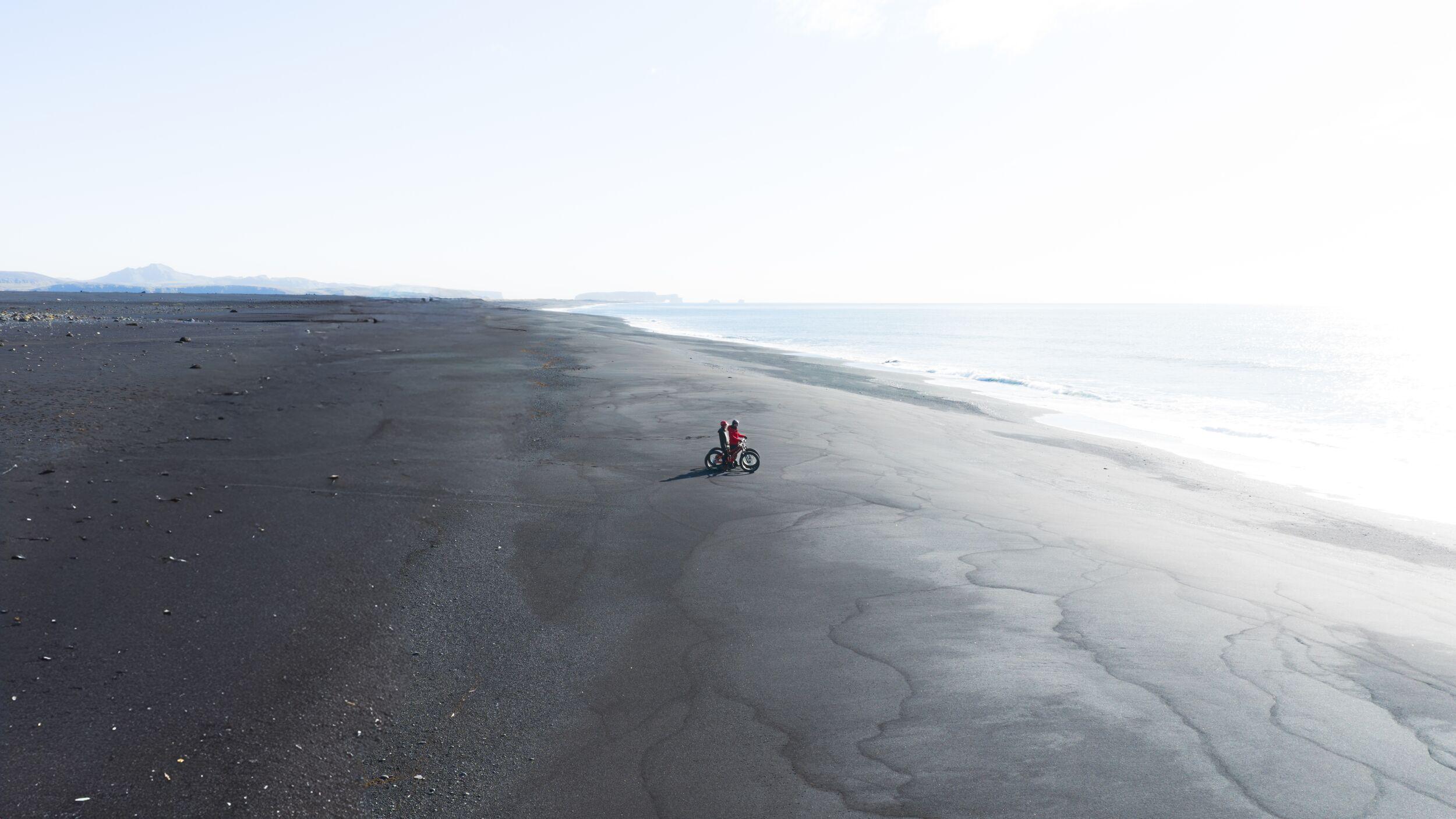 People on a bikes on a black beach