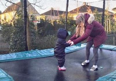 Moeder en kind springen hand in hand op de trampoline