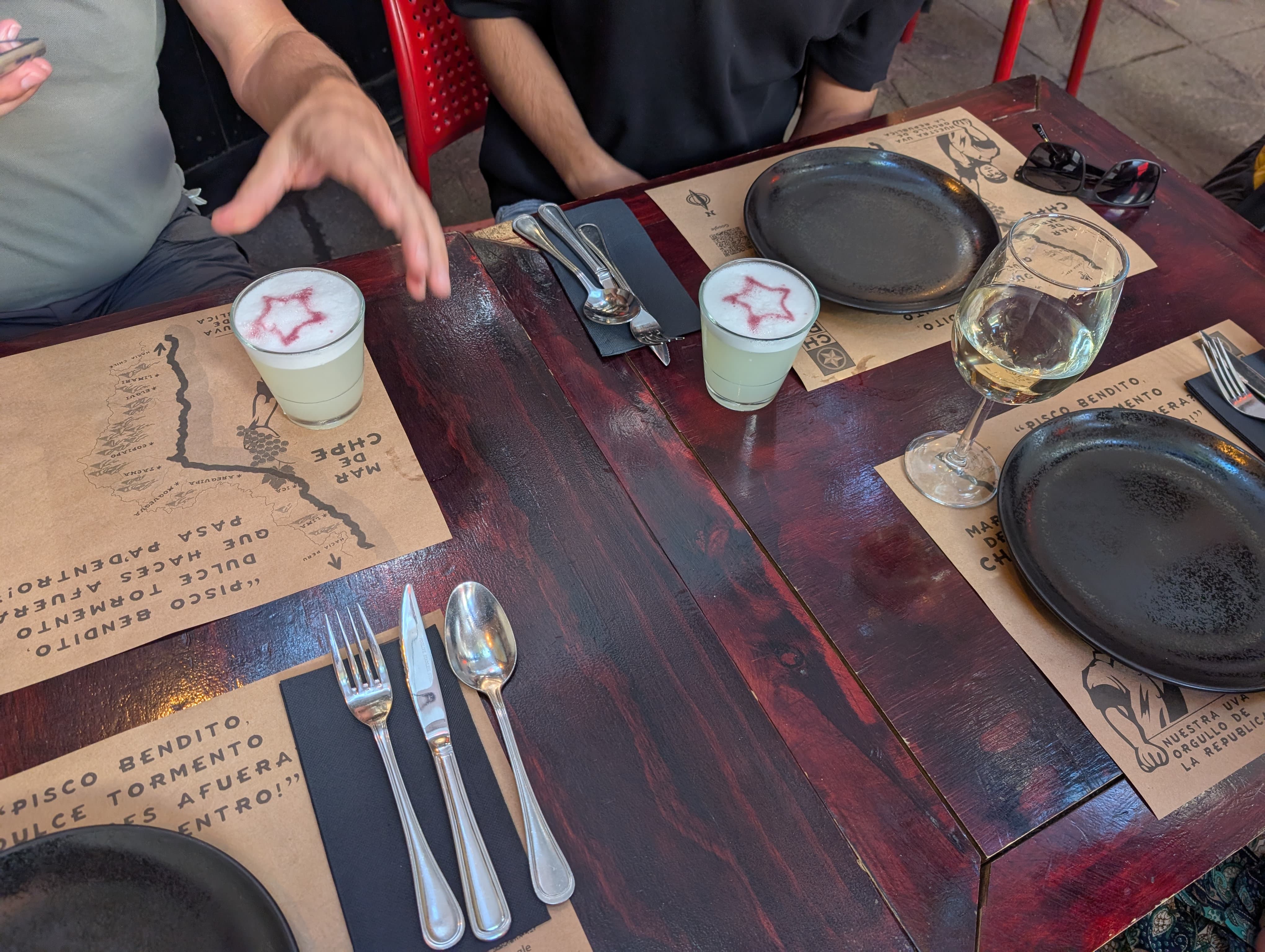 A restaurant table set with plates, cutlery and a menu written in chalk