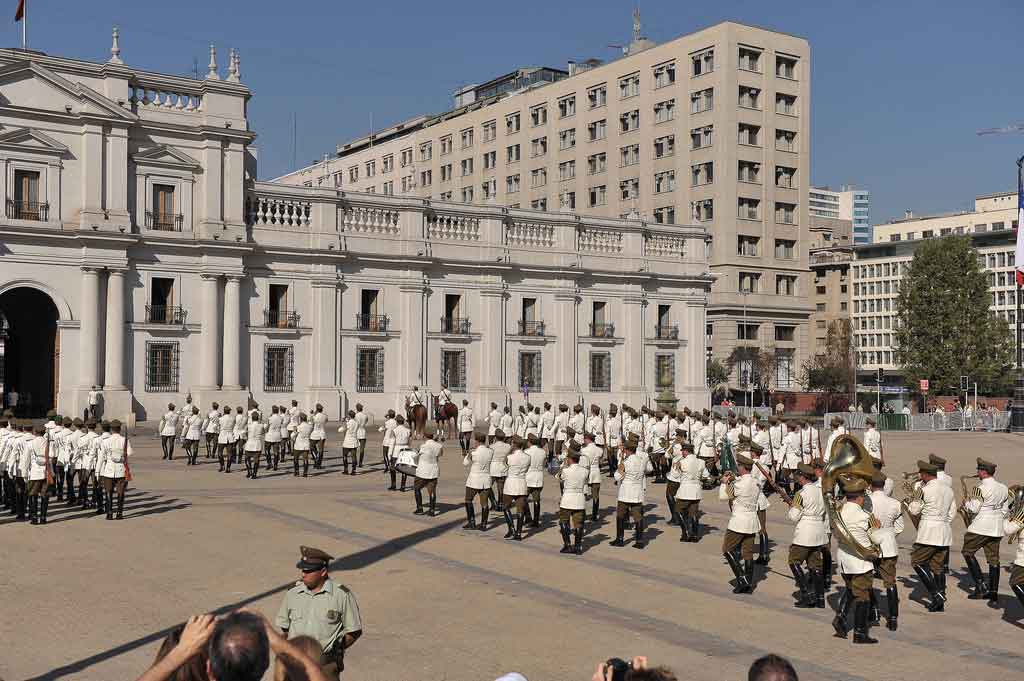 The presidential guard band marching in white ceremonial uniforms in front of La Moneda