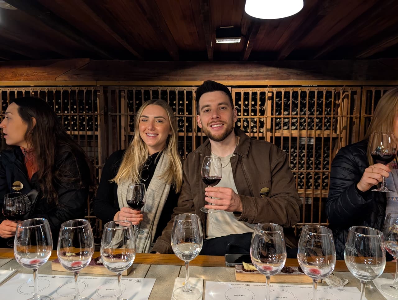 Three friends toasting with wine glasses at the cellar tasting table