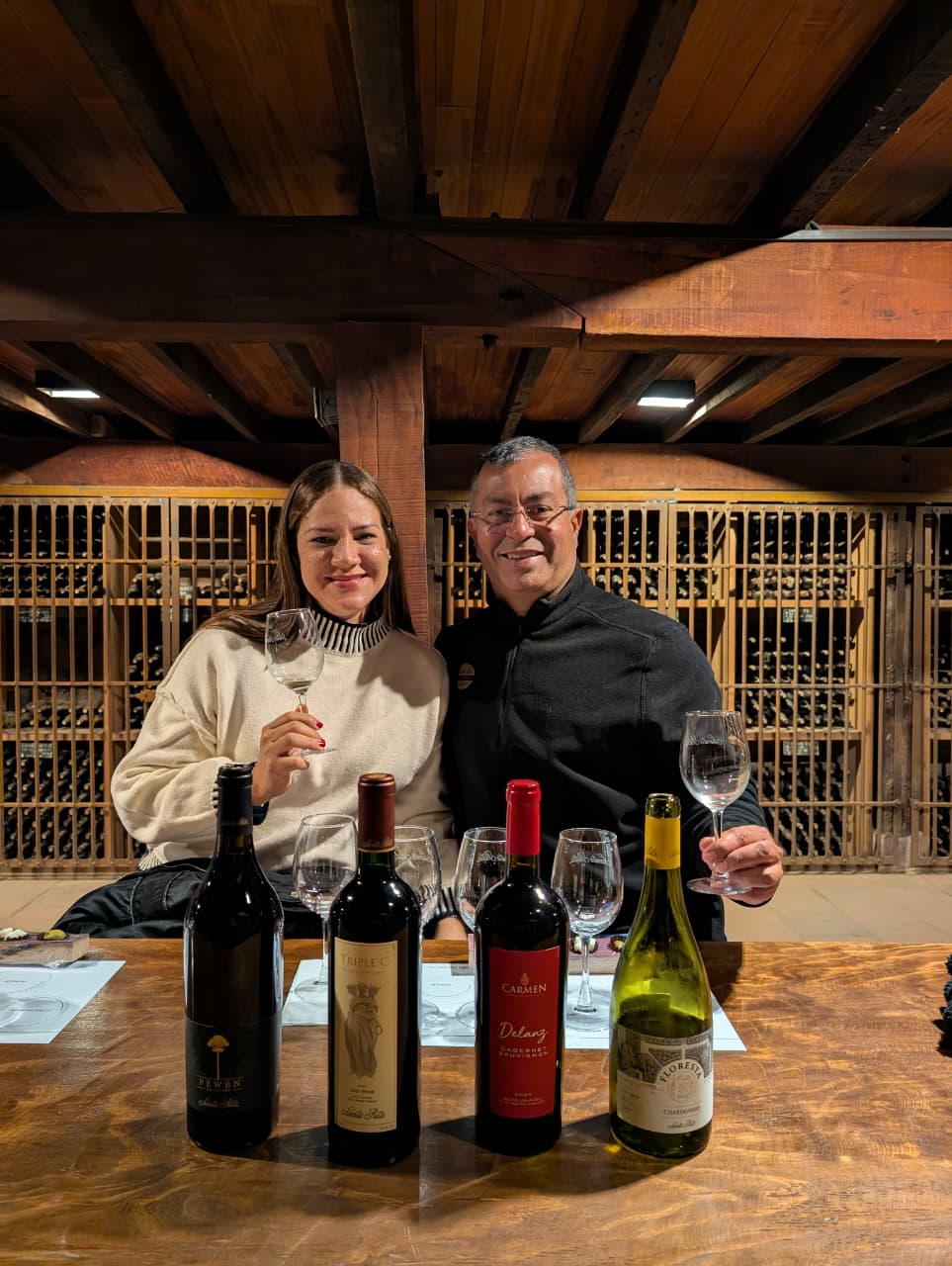 A couple holding wine glasses beside four bottles of Santa Rita wine