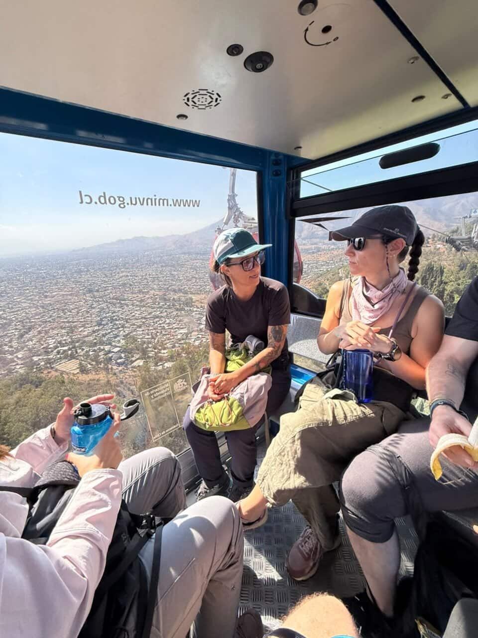 Passengers looking out from inside a cable car cabin over the city below