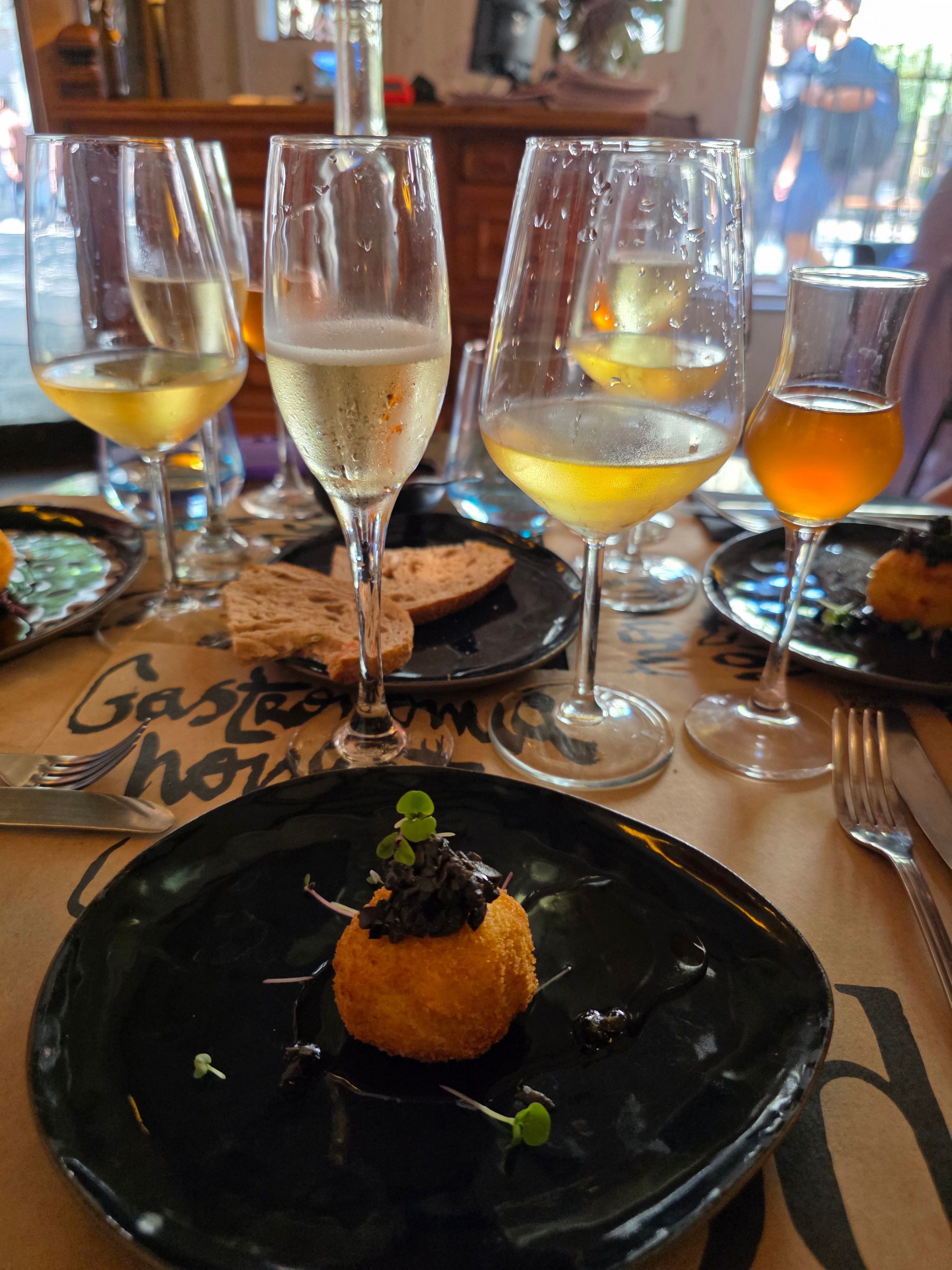 Glasses of white and orange wine on a restaurant table beside a plated dessert