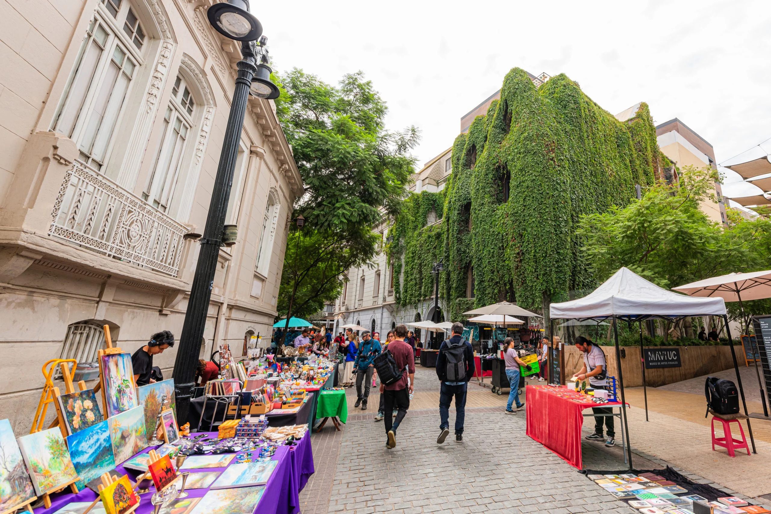 A lively street market lined with stalls along a leafy Lastarria street