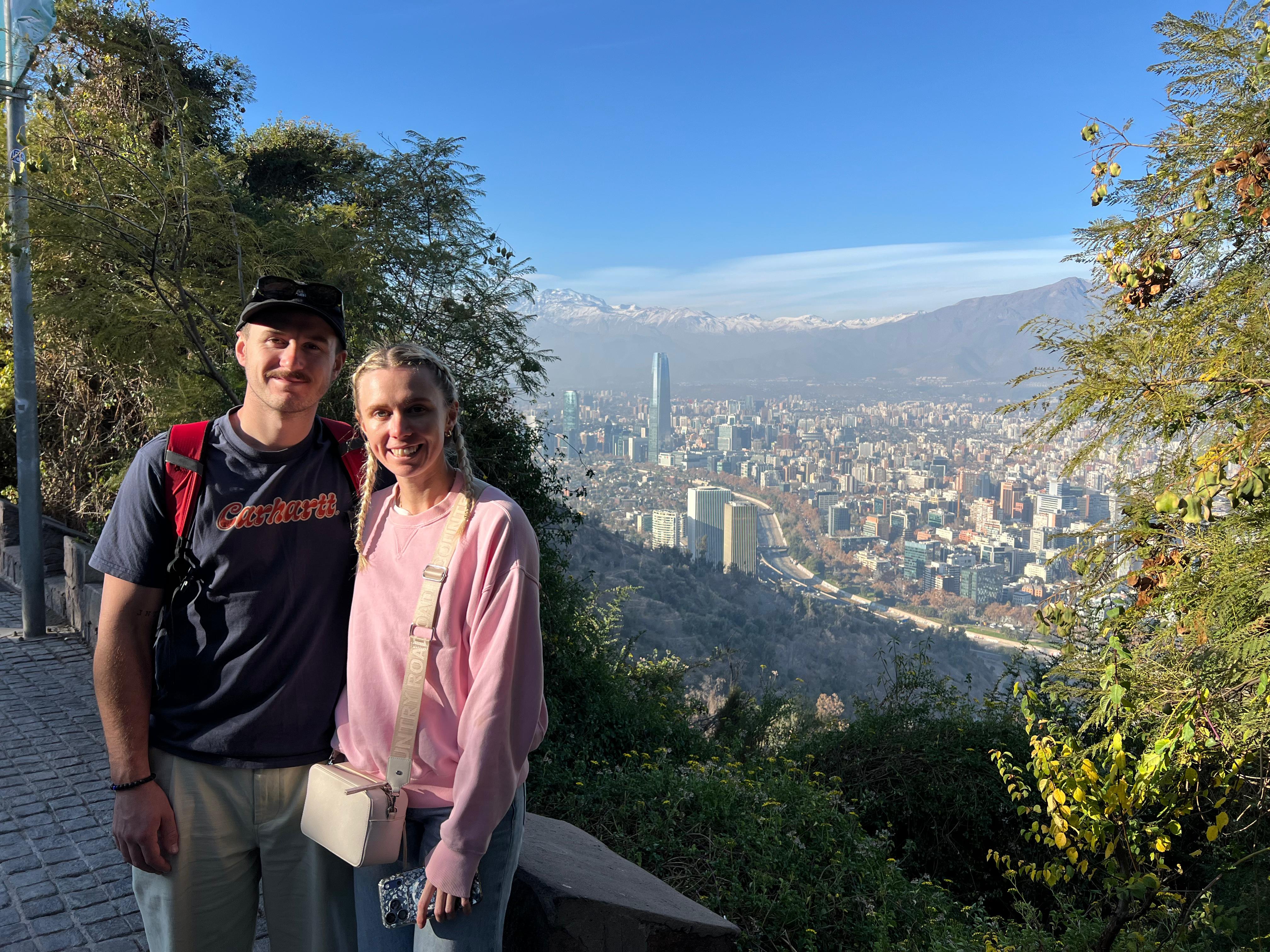 A couple posing together with the city and mountains spread out behind them
