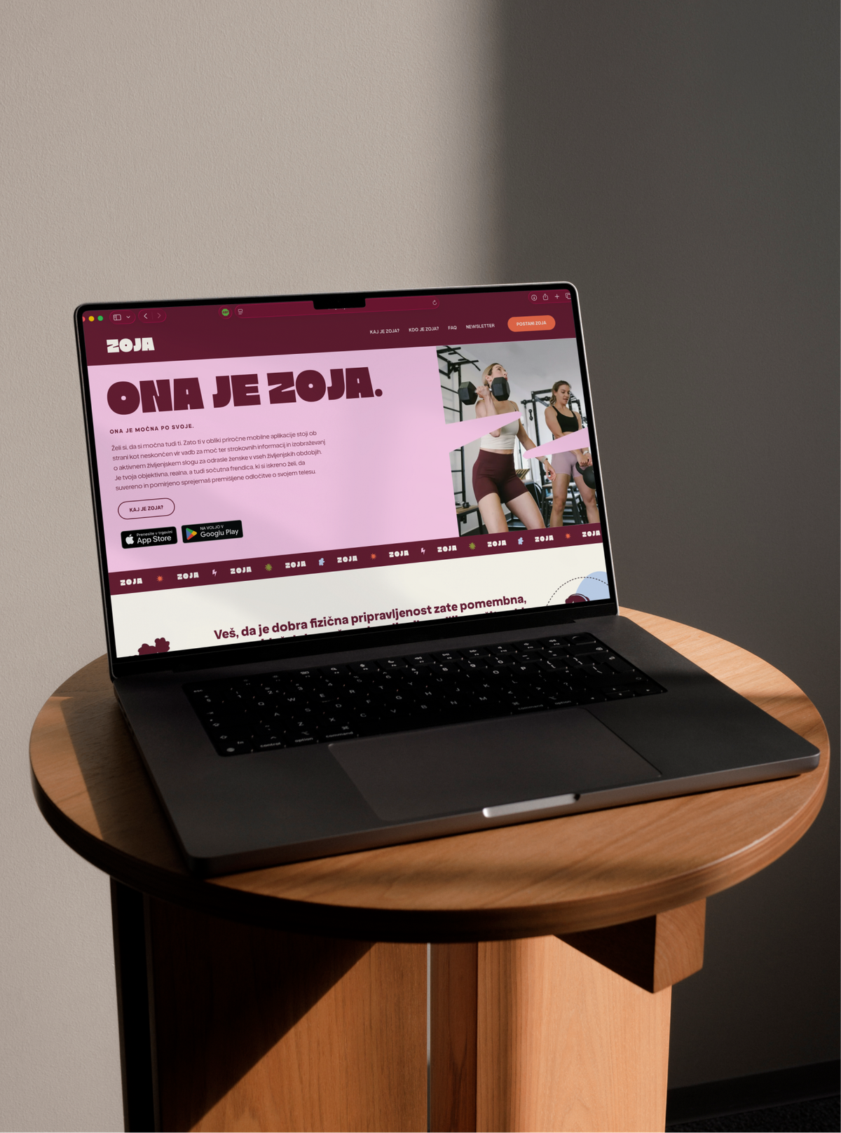 A laptop on a round wooden stool showing the Zoja website, headlined "Ona je Zoja."