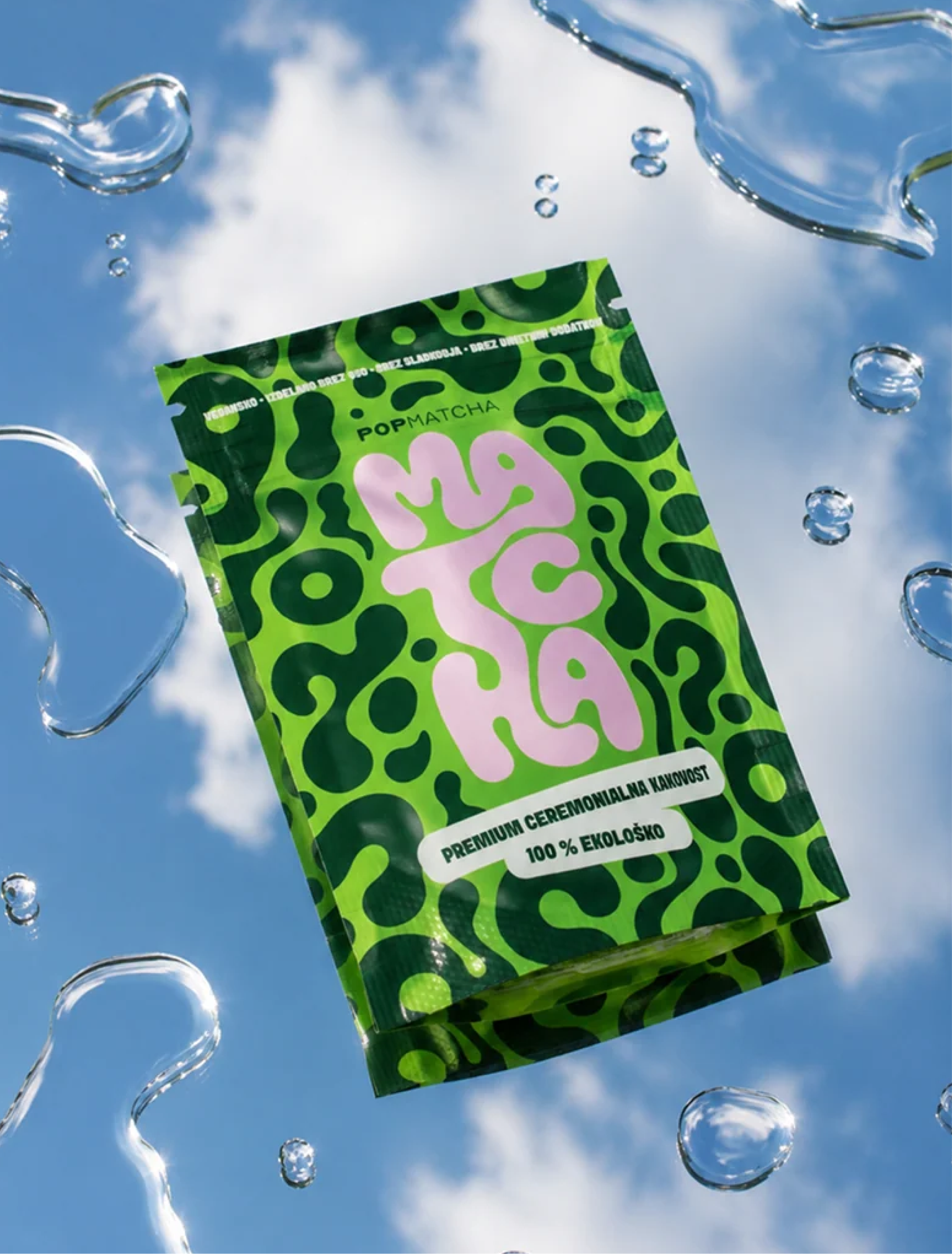 A green Pop Matcha pouch with stacked pink "Matcha" lettering, against blue sky and water drops.
