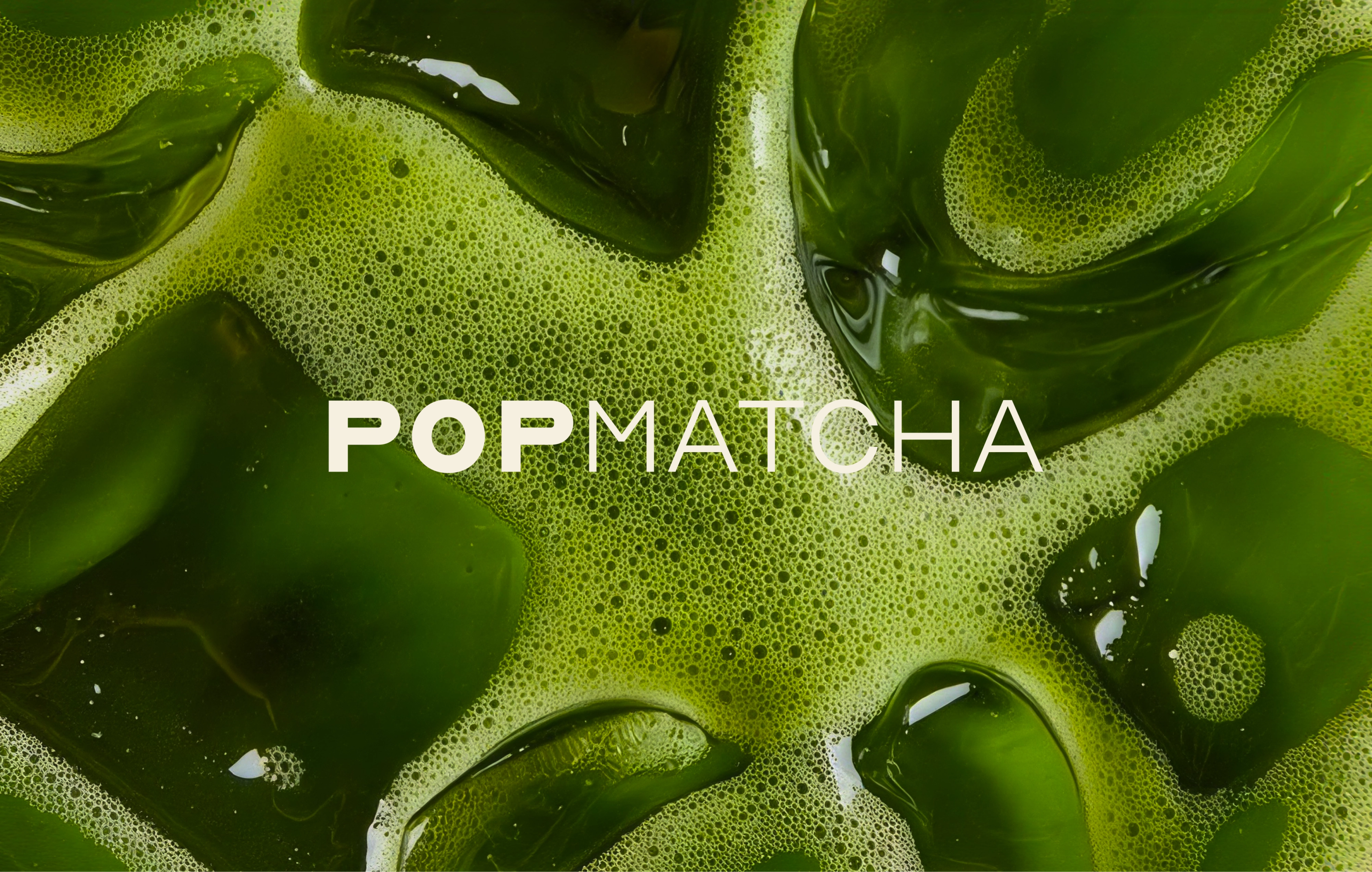 The Pop Matcha wordmark in cream over a close-up of frothy green matcha and ice cubes.