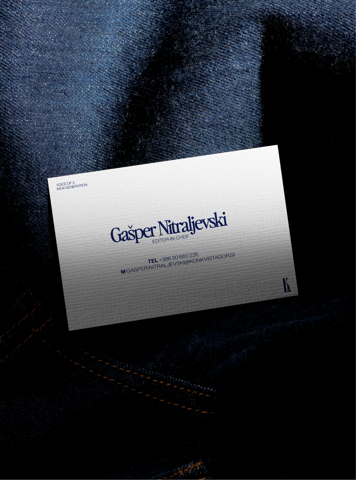 The editor-in-chief's business card lying on dark denim.