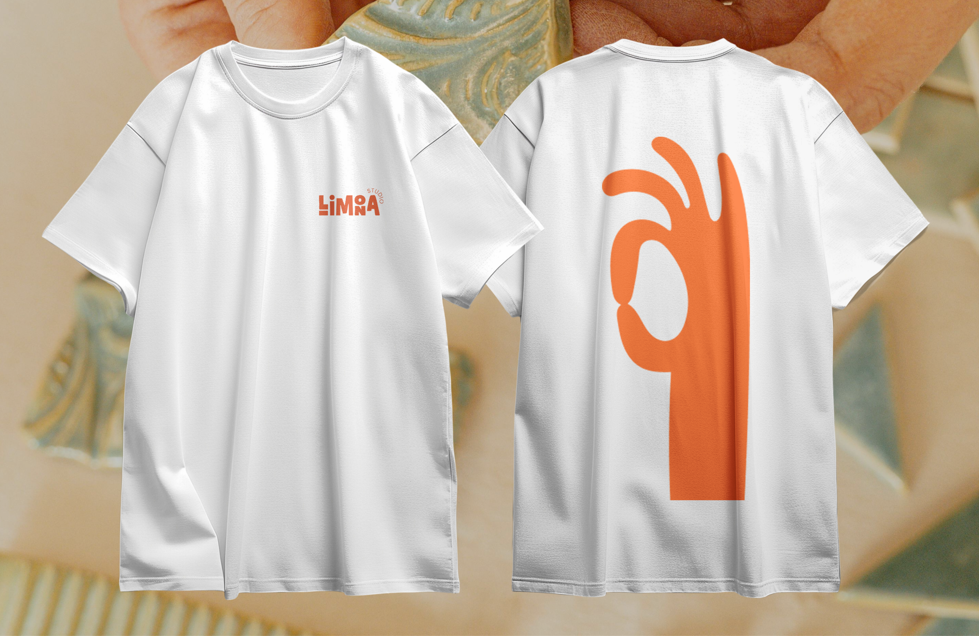 Front and back of a white Studio Limona T-shirt: a small orange logo, and a large orange OK hand.