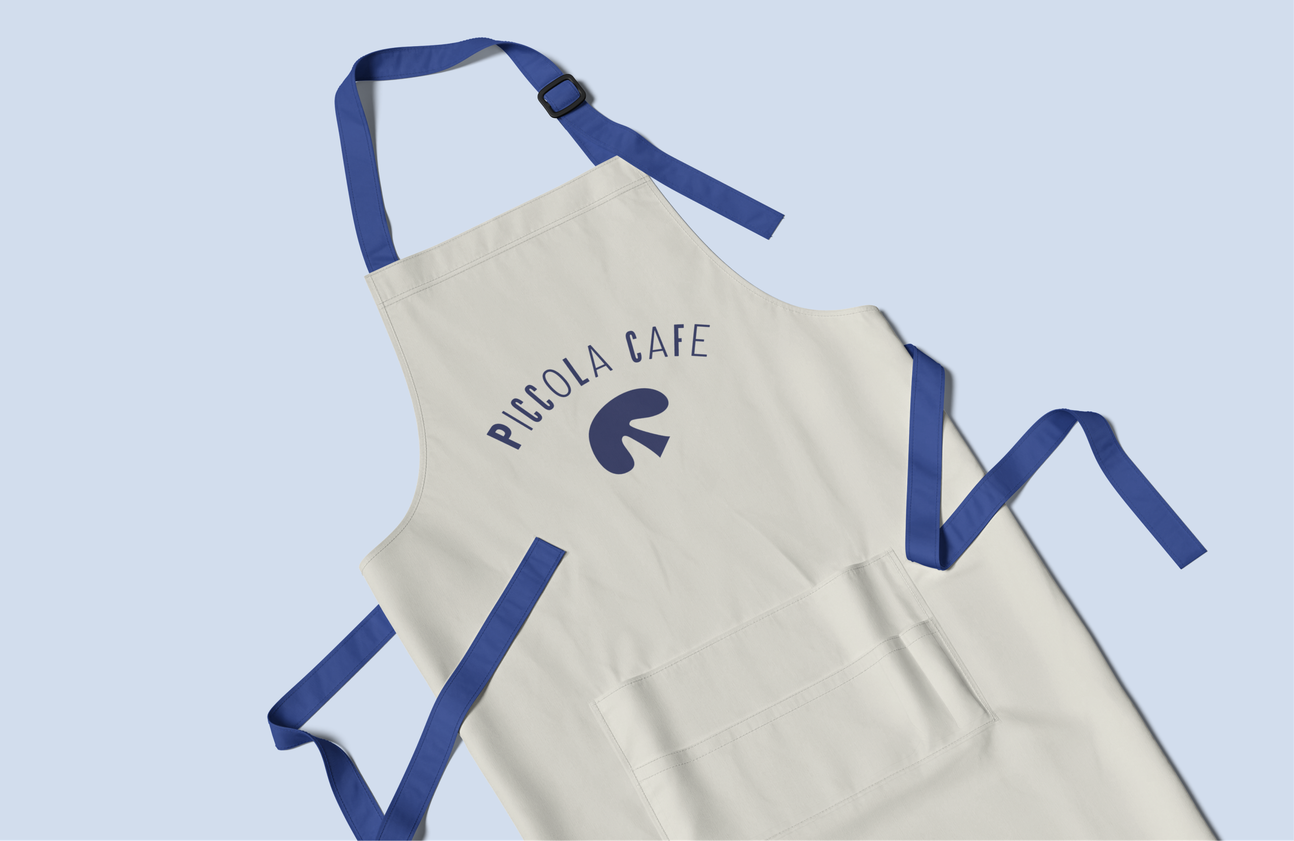 A cream apron with blue straps and the Piccola Cafe logo.