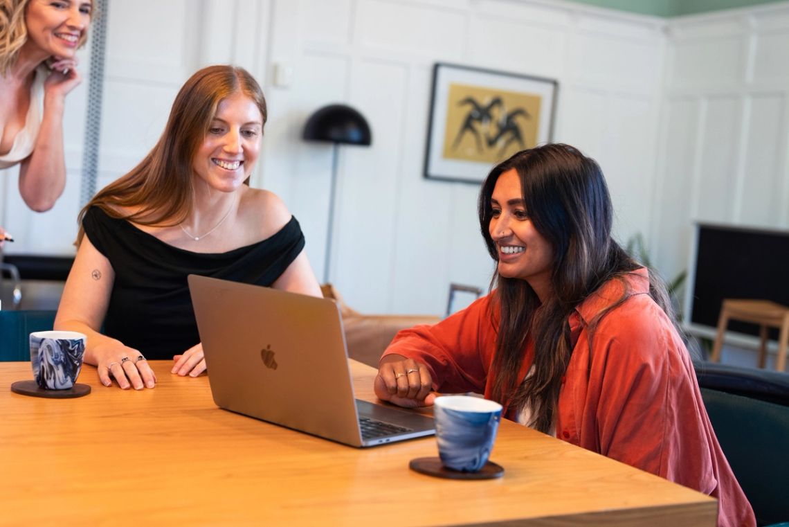 Two Done By Nine marketers looking at the same laptop screen across the studio table