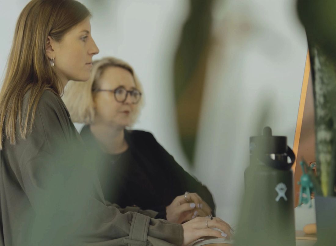 Two Done By Nine marketers side by side at a desk, one typing while both watch the screen