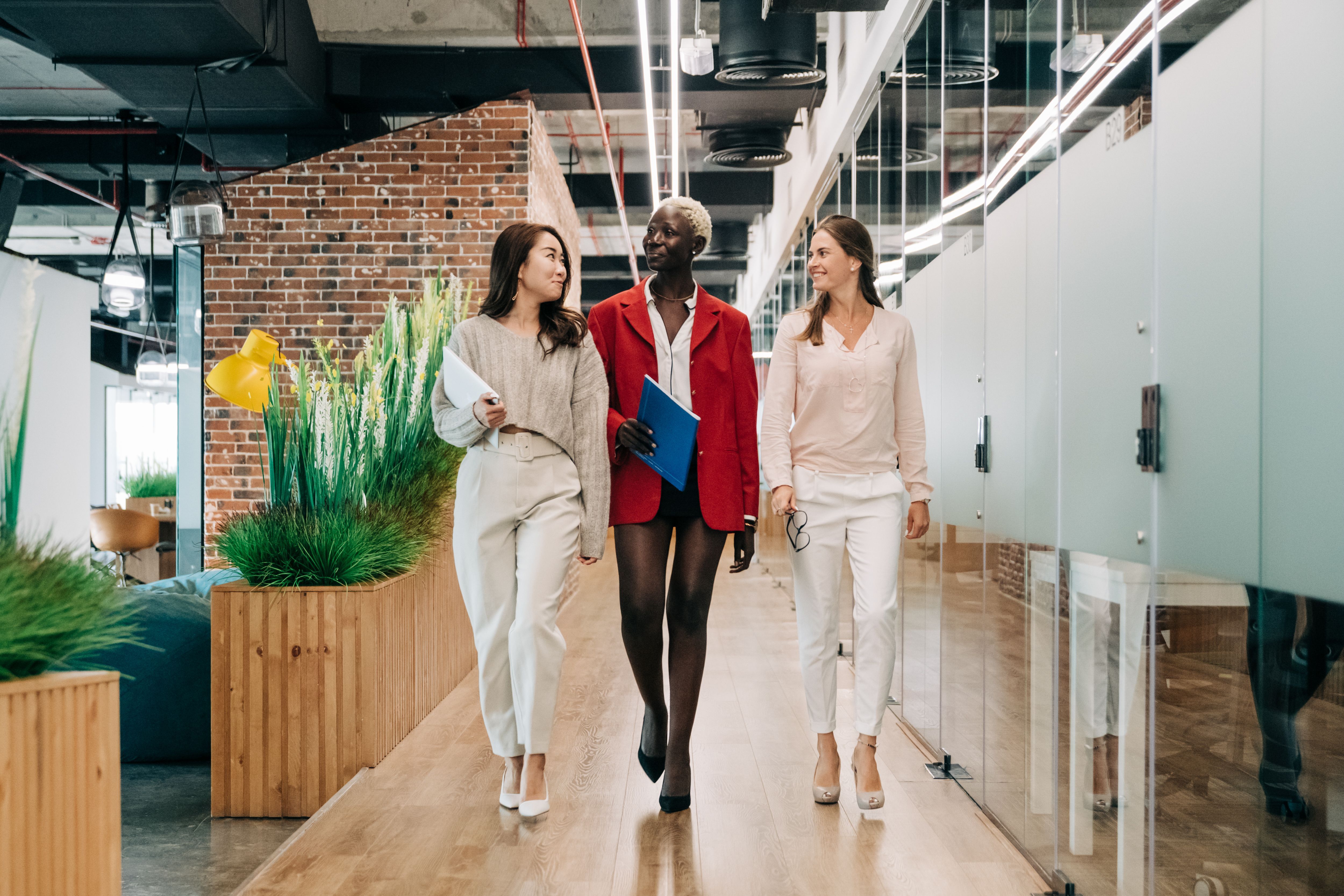 Three colleagues walking through a bright, clean office corridor