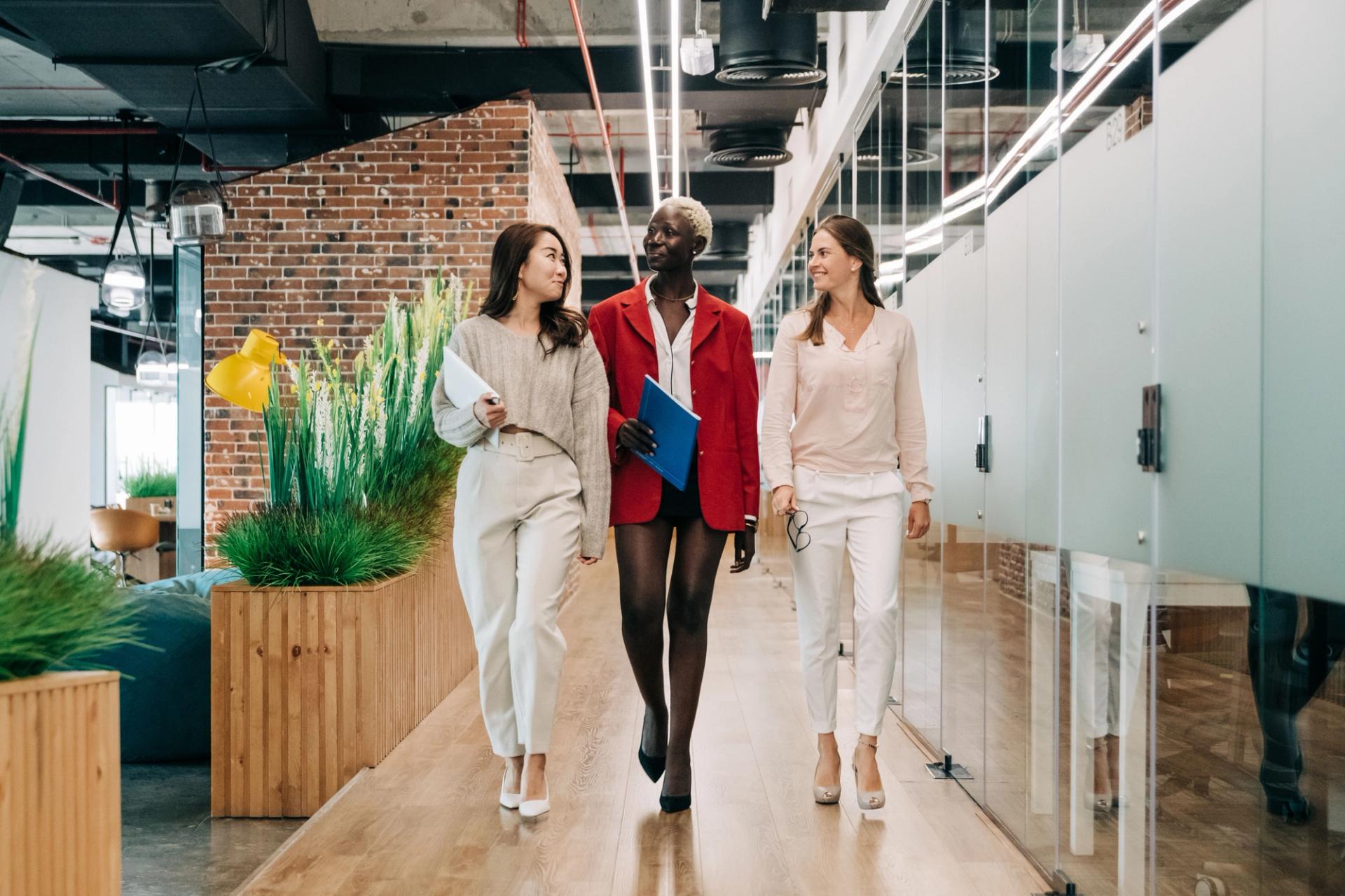 Three colleagues walking through a bright, clean office corridor