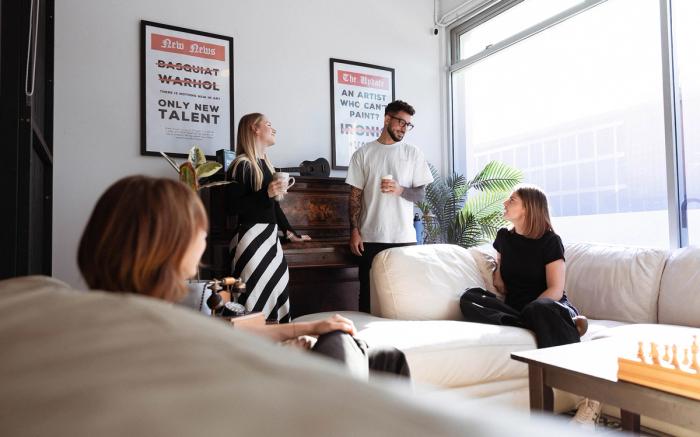 Four people socializing in a bright, modern room with a white sofa.