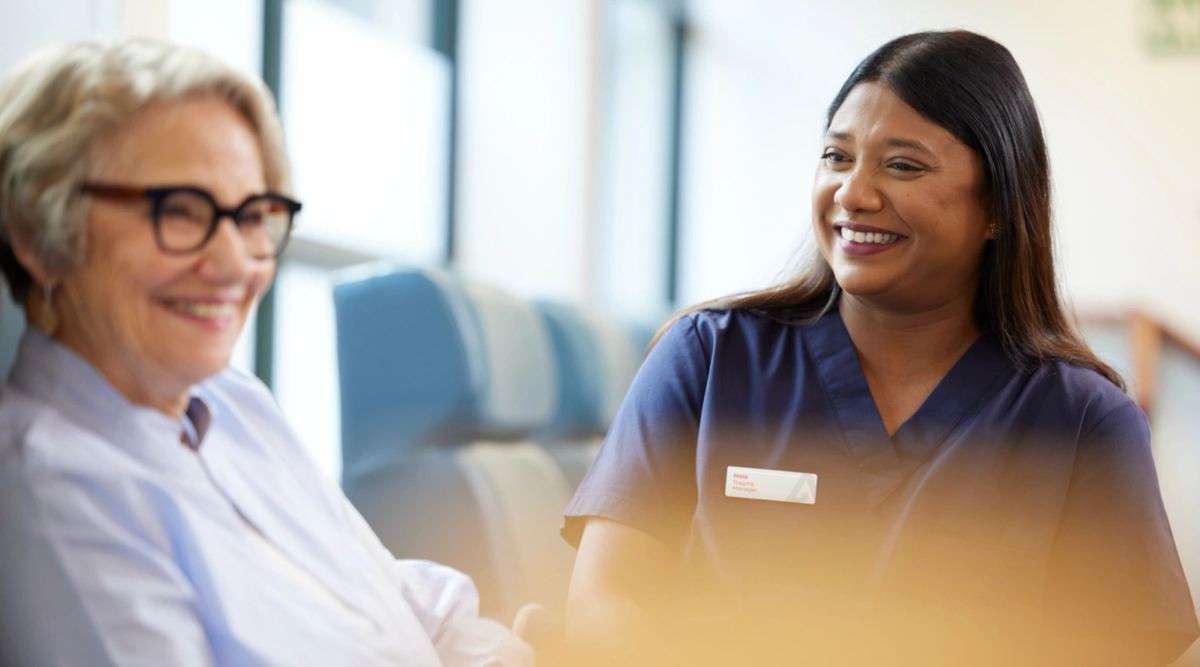 Smiling healthcare worker and older patient interacting.