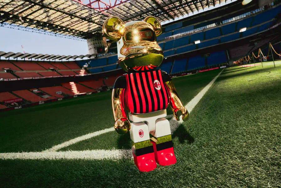AC Milan celebrates its 125th anniversary with a special edition BE@RBRICK collaboration, featuring collectible figures in the club’s iconic red and black stripes. The partnership with Medicom Toy includes BE@RBRICK figures in three sizes: 100%, 400%, and 1000%, all adorned with AC Milan’s traditional home kit design and finished in metallic gold. This collection honors the club’s rich legacy in Italian football, boasting 19 Serie A titles. The design contrasts with the fierce image envisioned by founder Herbert Kilpin, who described the team as “devils” in “red like fire and black like fear.” This collaboration adds to AC Milan’s cultural partnerships, including ties with Off-White™, minority stakeholders Drake and LeBron James, and previous collaborations with the New York Yankees. Available now on AC Milan’s online store, the limited edition 1000% figure is priced at €1,250 ($1,379), and the 400% and 100% set at €280 ($319)