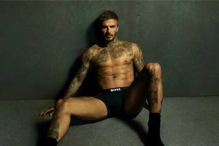 David Beckham wearing white BOSS ONE boxer briefs while seated in a minimalist New York apartment, photographed in black and white