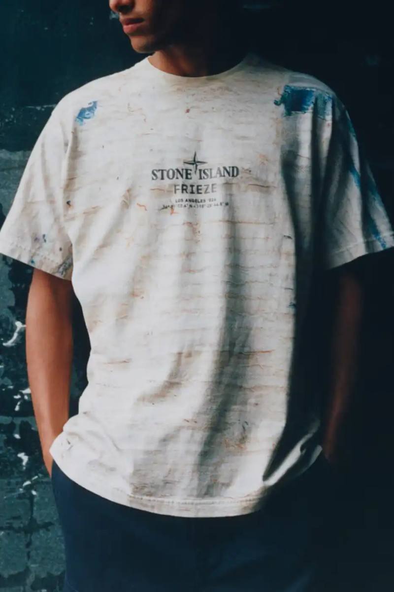 STONE ISLAND JAMAL CYRUS FRIEZE LA 2026 SHIRT A white t-shirt featuring black and grey abstract digital prints inspired by archival documents and historical collage.