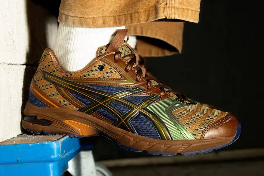 ASICS GEL-DS Trainer 14 sneaker designed by Kiko Kostadinov, showing asymmetrical lacing system and multi-textured upper in gradient colorways. Four shoes displayed featuring Waterfall, Desert Camp, Dark Mustard, and Midnight color combinations.
