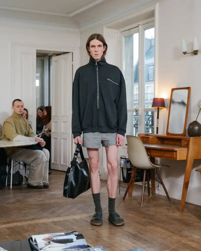 Camiel Fortgens Fall/Winter 2026 collection shown in Paris apartment, featuring garments made from domestic materials like curtain pleats and sofa leather in earthy tones.