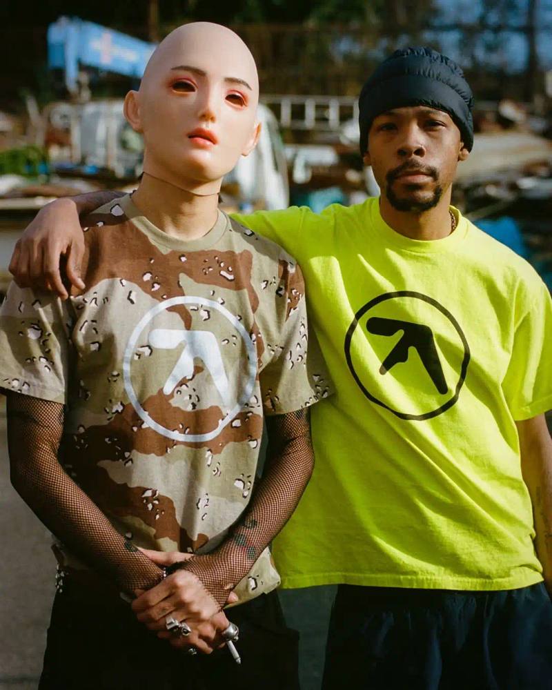 Supreme Supreme x Aphex Twin capsule collection lookbook image showing clothing items featuring iconic Aphex Twin album artwork and logos, including the distinctive logo designed by Paul Nicholson.
