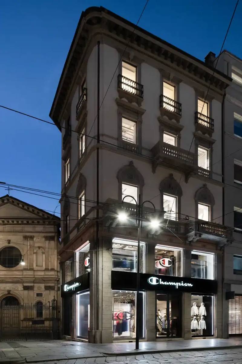 Article about Champion's new Milan flagship store opening on Via Torino 19, with details on store layout, design concept, and community initiatives.